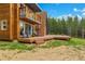 View of the wooden back deck with stairs and the forest beyond the home at 509 Paiute Rd, Evergreen, CO 80439