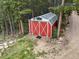 Exterior aerial view of a red barn with white trim and solar panels in a wooded area at 509 Paiute Rd, Evergreen, CO 80439