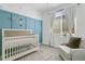 Adorable Bedroom featuring a wooden crib, blue wall paneling, and a window with white curtains at 3111 Youngheart Way, Castle Rock, CO 80109