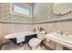 Traditional bathroom showcasing a clawfoot tub, toilet, pedestal sink, and patterned wallpaper under the window at 1284 N Corona St # B6, Denver, CO 80218