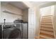 Well-organized laundry area features modern washer and dryer, convenient shelving, and close proximity to stairs at 3176 Depew St, Wheat Ridge, CO 80214