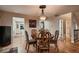 Charming dining room with a wooden table set for four, complemented by elegant lighting and hardwood floors at 25779 E Jamison Cir, Aurora, CO 80016