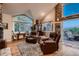 Bright living room boasts vaulted ceilings, stone accents, hardwood floors, and large windows with beautiful wooded views at 25779 E Jamison Cir, Aurora, CO 80016