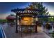 Outdoor kitchen with a built-in grill, bar seating, stone accents, and decorative fork and spoon art at 25779 E Jamison Cir, Aurora, CO 80016