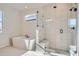 Modern bathroom with a freestanding tub, glass-enclosed shower, and white tile throughout at 2690 E 102Nd Pl, Thornton, CO 80229