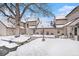 Backyard view of townhomes, featuring a snow-covered ground, a mature tree, and well-maintained exteriors at 2141 S Victor St # B, Aurora, CO 80014