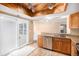 Open floor plan kitchen showcasing wooden cabinets, a stainless steel dishwasher, and a unique beamed ceiling with track lighting at 2141 S Victor St # B, Aurora, CO 80014