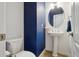 Stylish half bathroom featuring a pedestal sink, modern vanity and contrasting blue accent wall at 12248 Kittredge St, Commerce City, CO 80603