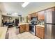 Spacious kitchen layout with stainless steel appliances, wooden cabinetry, and a connecting dining area at 14742 E Radcliff Pl, Aurora, CO 80015