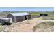 Brown metal barn with a single stall and fenced area at 45425 Wolf Creek Dr, Bennett, CO 80102