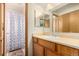 Bathroom with wood vanity, shower/tub, and a patterned curtain at 6119 Zenobia Ct, Arvada, CO 80003