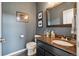 Half bathroom offering a modern black vanity with granite counter and blue accent wall at 9158 Forest St, Firestone, CO 80504