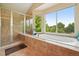 Bright bathroom with a large soaking tub, glass enclosed shower, and a scenic view at 9158 Forest St, Firestone, CO 80504