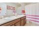 Charming bathroom featuring double sinks, a vanity with cabinets, and a pink-striped shower curtain at 3008 Echo Park Dr, Castle Rock, CO 80104