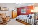 Cozy bedroom with a rocking chair, dresser, and striped bedding, offering a relaxing atmosphere at 5370 W 74Th Ave, Arvada, CO 80003