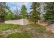 Rear exterior of home with a stucco wall and mature trees surrounding the property at 17995 Minglewood Trl, Monument, CO 80132