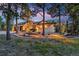 Beautifully lit stucco home at dusk with charming front yard and mature trees at 17995 Minglewood Trl, Monument, CO 80132