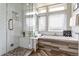 Bright bathroom with a glass-enclosed shower, soaking tub with wood accents, and large windows at 3227 Quivas St # 1, Denver, CO 80211