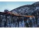Antique lighted passenger train traversing through a mountainous forest at 1890 Argentine St # D203, Georgetown, CO 80444