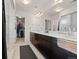Bathroom with double sinks, dark wood cabinetry, walk-in closet, and bright vanity lighting at 5318 Truckee St, Denver, CO 80249