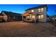 A view of the backyard at dusk, highlighting the covered patio and spacious lawn at 12863 Crane River Dr, Firestone, CO 80504