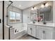 Modern bathroom featuring dual sinks, quartz countertops, and a tub with a shower at 12863 Crane River Dr, Firestone, CO 80504