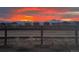 Scenic view of a colorful sunset sky over the neighborhood homes, framed by a rustic wooden fence and distant mountains at 12863 Crane River Dr, Firestone, CO 80504