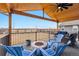 Covered outdoor patio with seating area overlooking a fenced-in field at 12863 Crane River Dr, Firestone, CO 80504