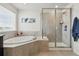 This bright bathroom features a soaking tub, and glass enclosed shower near a window for natural light at 236 Back Nine Dr, Castle Pines, CO 80108