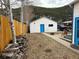 Charming backyard with a white-sided garage featuring a bright blue door and wooden privacy fence at 215 Colorado Blvd, Idaho Springs, CO 80452