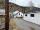 Charming home exterior with white siding, blue trim, gravel driveway and a mountain backdrop at 215 Colorado Blvd, Idaho Springs, CO 80452