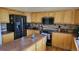 Well-lit kitchen with wooden cabinets, black appliances, and a center island at 8024 W 95Th Way, Broomfield, CO 80021