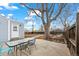 The backyard patio features a table set, adjacent to a house with a fenced-in yard and mature tree providing shade at 1780 S Umatilla St, Denver, CO 80223