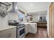 Open kitchen with stainless steel stove, range hood, and access to living area at 1780 S Umatilla St, Denver, CO 80223
