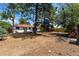 Spacious backyard with mature trees, a stone fireplace, and a red roof home at 3338 W Arlington Ave, Littleton, CO 80123