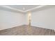 Empty bedroom with light-colored walls and wood-look flooring, featuring a tray ceiling and closet access at 17530 E 95Th Ave, Commerce City, CO 80022