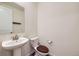 Half-bathroom features a pedestal sink, a white toilet with a wood seat, and a decorative towel rack at 17530 E 95Th Ave, Commerce City, CO 80022
