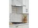 Close up of the gas range with a stainless steel vent hood and white marble backsplash at 2317 S Galapago St, Denver, CO 80223