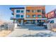 View of a condo building with orange and white facade, and parking in front at 2876 W 53Rd Ave # 106, Denver, CO 80221