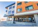 Exterior view of a modern condo building with orange and white accents and large windows at 2876 W 53Rd Ave # 106, Denver, CO 80221
