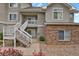 Exterior of building featuring white staircases, stucco facade, brick accents, and landscaped flower bed at 1801 S Dunkirk St # 108, Aurora, CO 80017