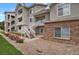 Condo exterior with white staircases, gray facade, brick accents, and landscaped with rocks and flower bushes at 1801 S Dunkirk St # 108, Aurora, CO 80017