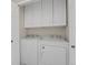 Bright laundry room includes a stacked washer and dryer and ample storage in the white upper cabinets at 1801 S Dunkirk St # 108, Aurora, CO 80017