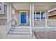Inviting front porch with a bright blue door, white railings, and ample natural light at 8545 Braun Loop, Arvada, CO 80005