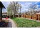 Spacious backyard showcasing a lush green lawn, mature trees, wooden fence, and brick-paved pathway at 13588 W Exposition Dr, Lakewood, CO 80228