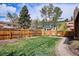 Private backyard boasts a well-maintained lawn, wood fence, and mature trees, creating a serene outdoor space at 13588 W Exposition Dr, Lakewood, CO 80228