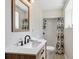 Well-lit bathroom with a modern vanity, stylish mirror, and shower with patterned curtain at 13588 W Exposition Dr, Lakewood, CO 80228