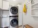 Modern laundry room featuring stacked washer and dryer, storage cabinets, and hanging rack at 13588 W Exposition Dr, Lakewood, CO 80228