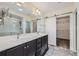 Elegant bathroom with dual vanities, a large mirror, and a shower with glass door, next to barn door closet at 10808 Salida St, Commerce City, CO 80022
