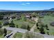 Aerial view showcasing a neighborhood surrounded by lush trees and open fields under a sunny sky at 18045 Sunburst Dr, Monument, CO 80132